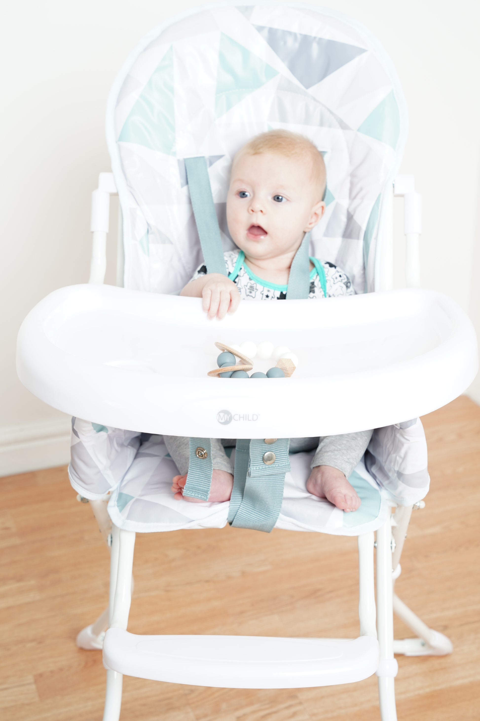Baby sitting in Pepper highchair with tray, front view