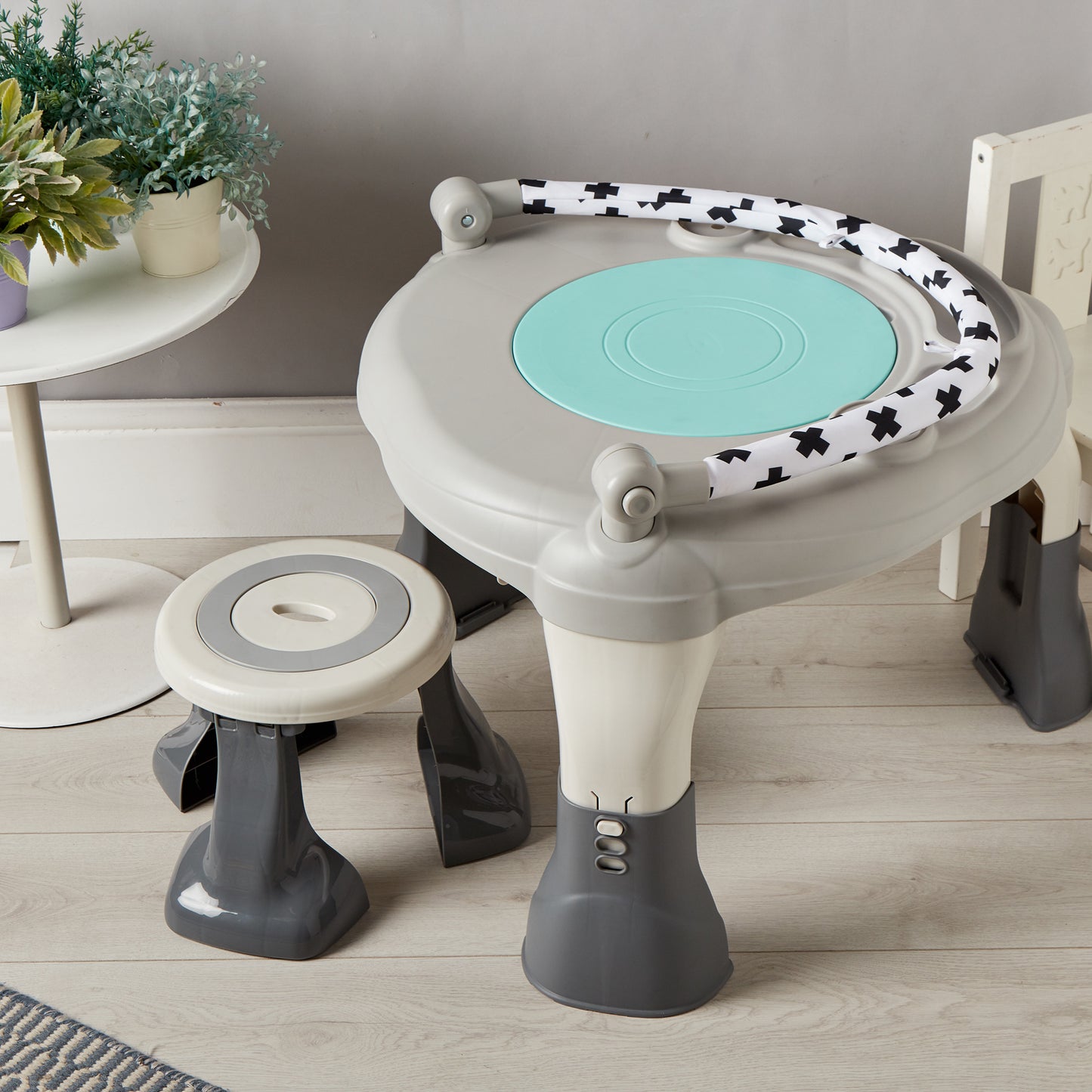 Children's play table and stool set with a light blue top and black and white patterned sides on a wooden floor.