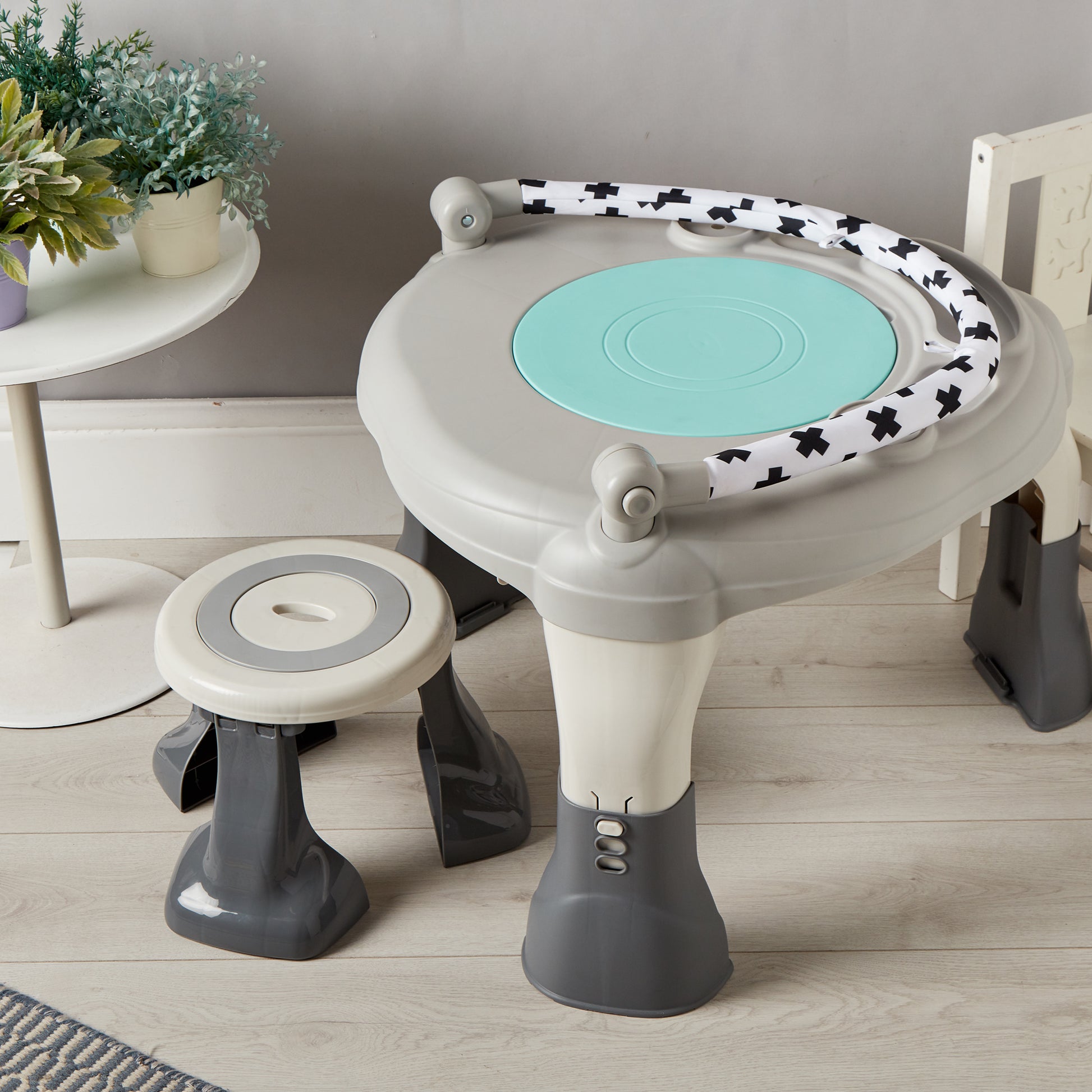 Children's play table and stool set with a light blue top and black and white patterned sides on a wooden floor.