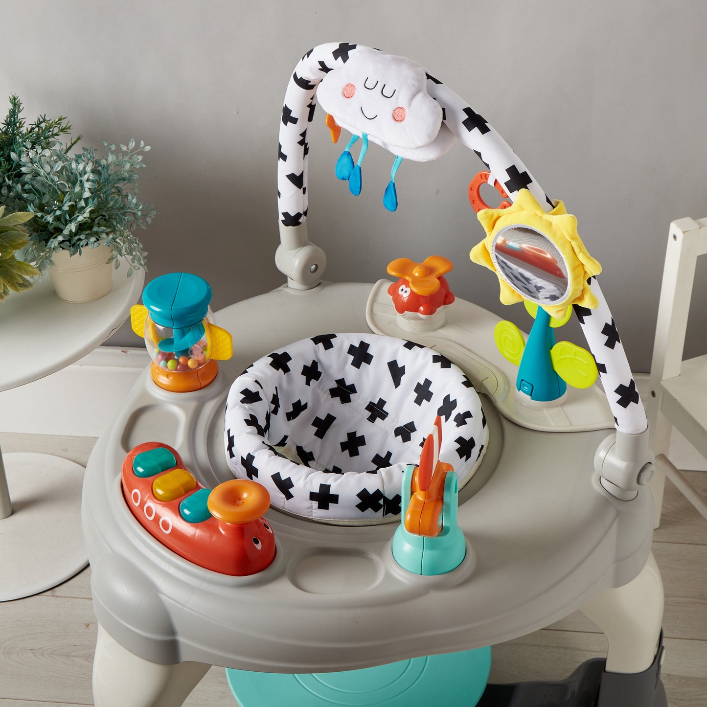 Baby activity center with toys and a cloud-shaped toy on a light gray background
