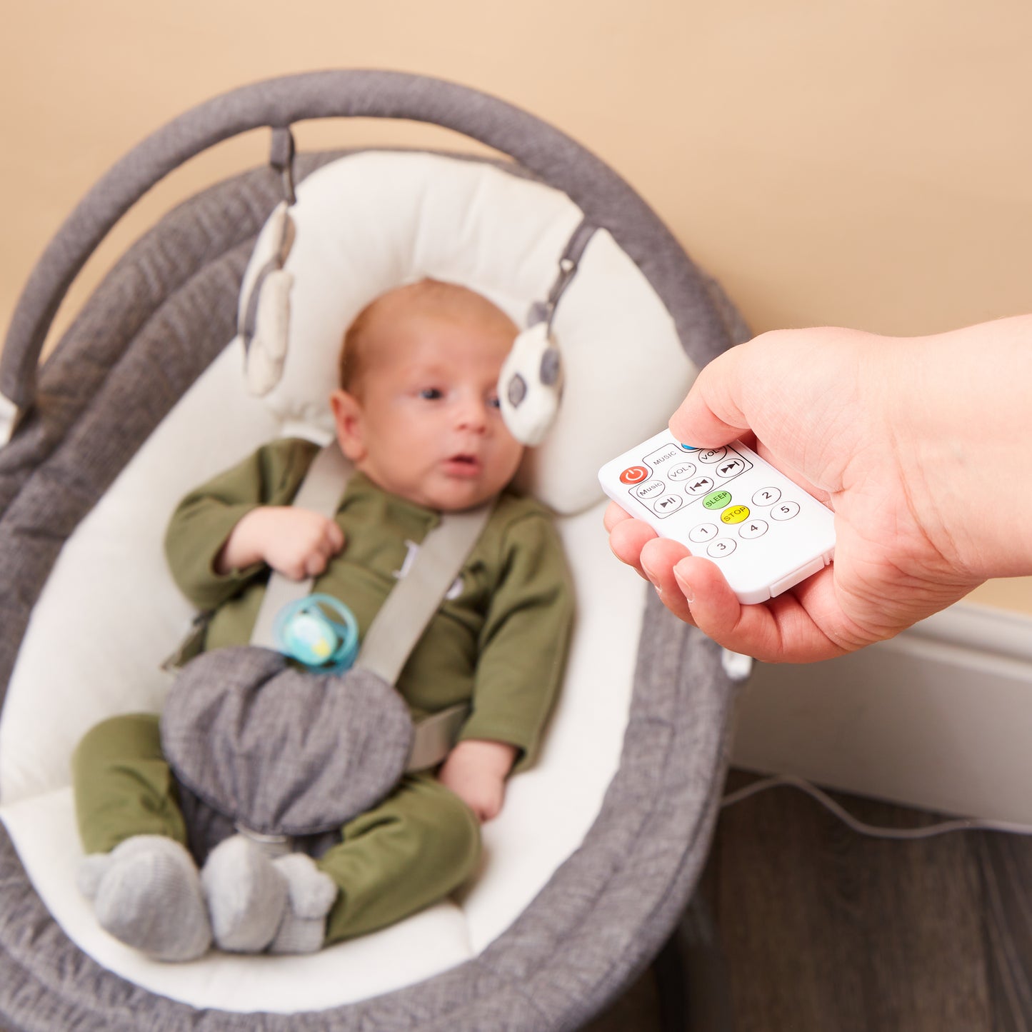 Close-up of baby in rocker with remote control for swing and music