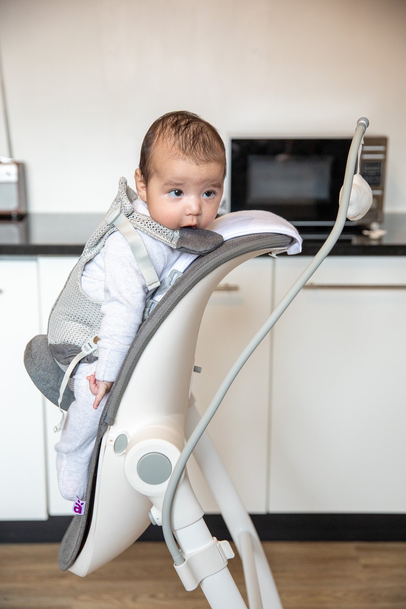 Baby sitting in BabyUp® colic & reflux support seat, side view